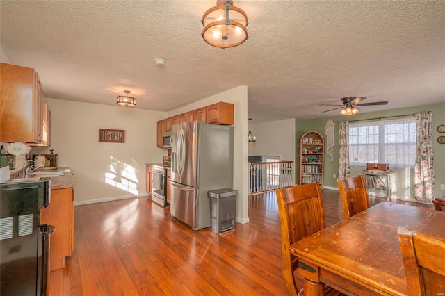 dining room with hardwood / wood-style flooring, ceiling fan, a fireplace, and sink