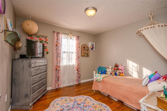 bedroom with a textured ceiling and dark hardwood / wood-style flooring