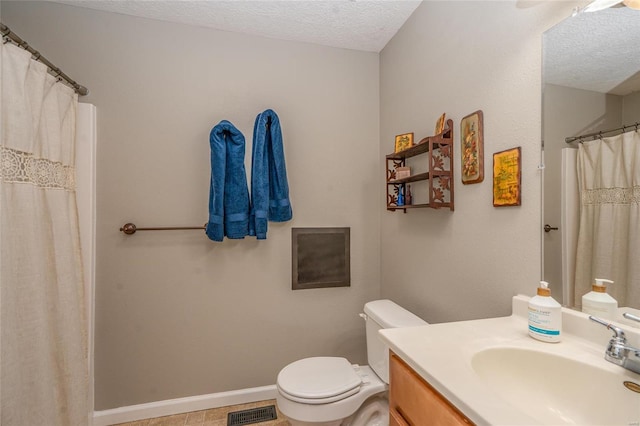 bathroom with vanity, toilet, and a textured ceiling