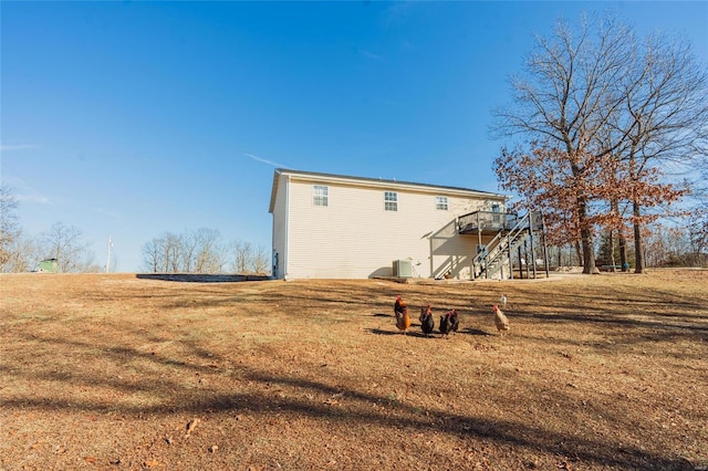 back of house with central AC, a deck, and a lawn