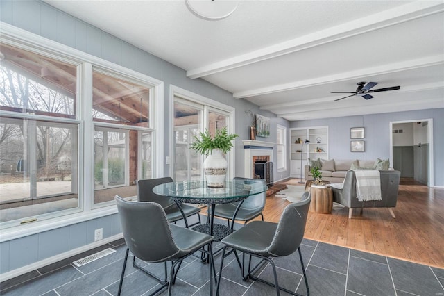 dining area with built in features, visible vents, dark wood finished floors, beamed ceiling, and a brick fireplace