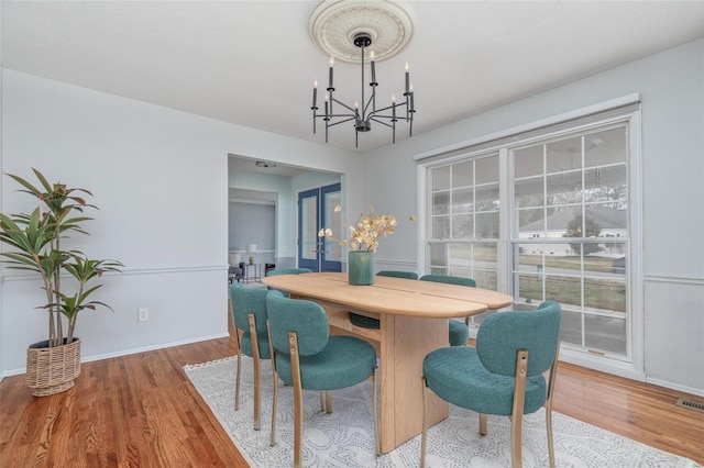 dining space with a chandelier, baseboards, and wood finished floors