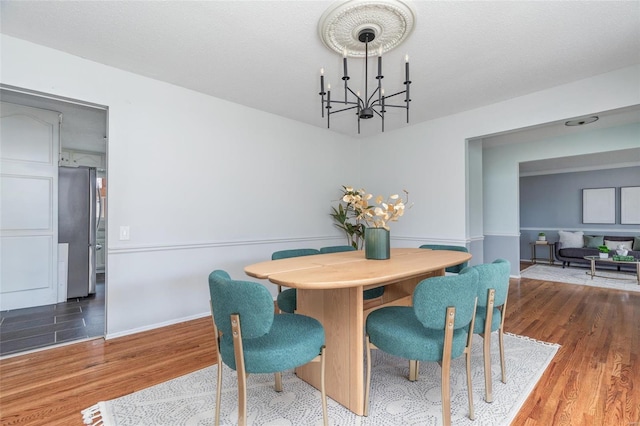 dining area featuring a chandelier, baseboards, and wood finished floors