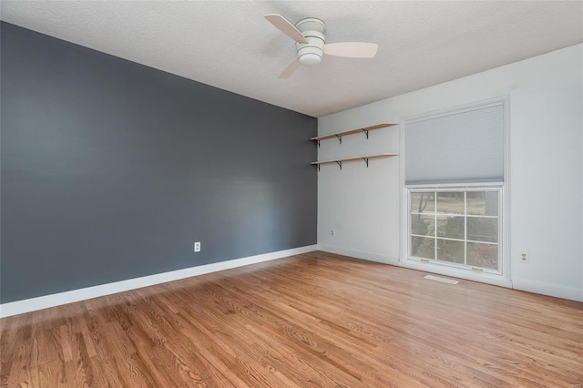 empty room featuring light wood-type flooring, visible vents, baseboards, and a ceiling fan