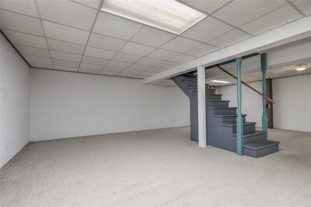 finished basement featuring stairs, a drop ceiling, and carpet flooring