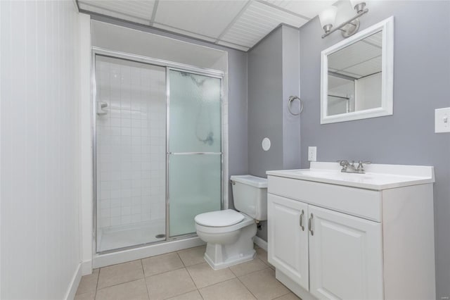 bathroom featuring toilet, a stall shower, vanity, baseboards, and tile patterned floors