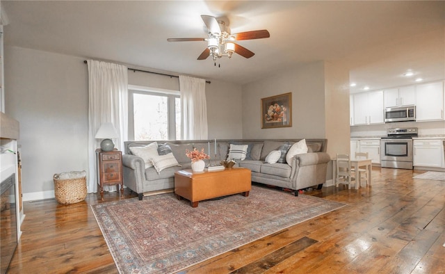 living room featuring dark wood-type flooring and ceiling fan