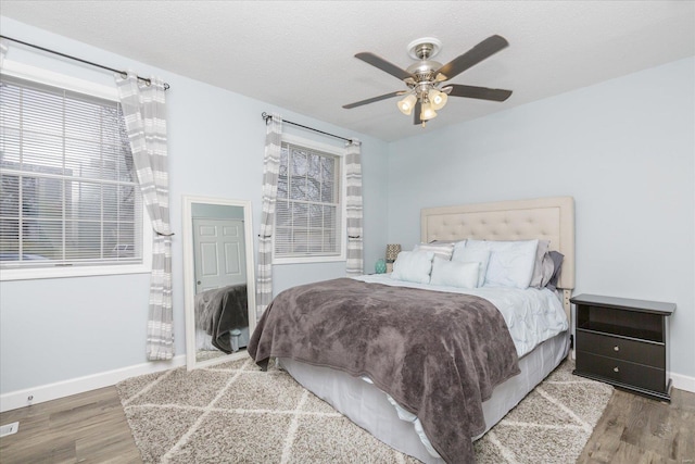 bedroom with hardwood / wood-style flooring, ceiling fan, and a textured ceiling