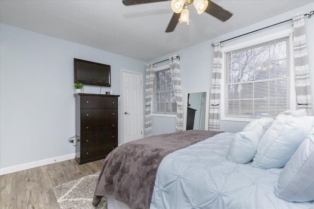 bedroom with ceiling fan, a textured ceiling, and light hardwood / wood-style flooring