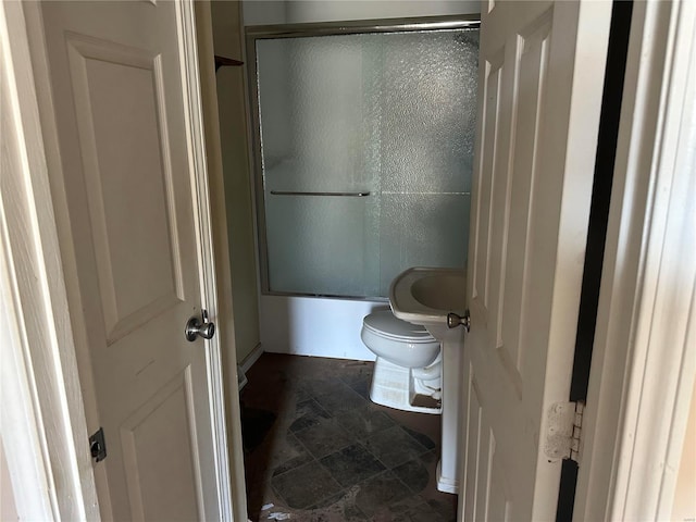 bathroom with shower / bath combination with glass door and toilet