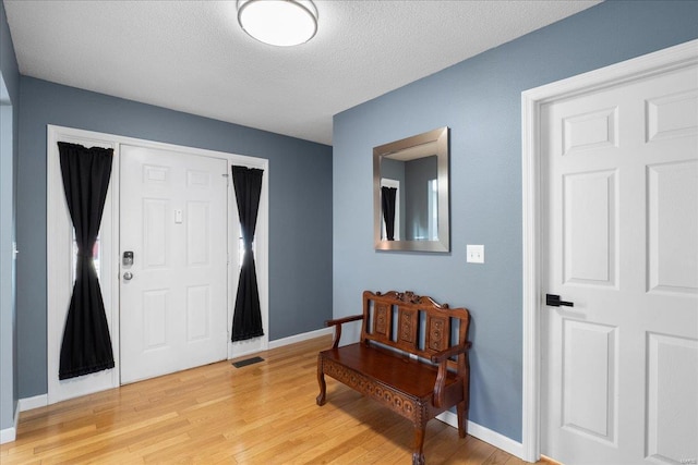 entryway with a textured ceiling and light hardwood / wood-style floors