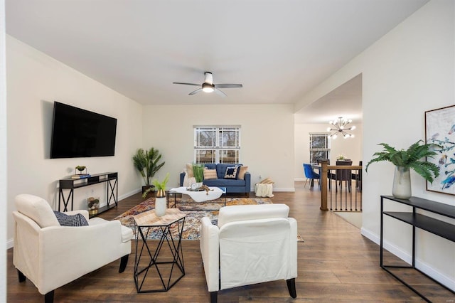 living room featuring ceiling fan with notable chandelier and dark wood-type flooring