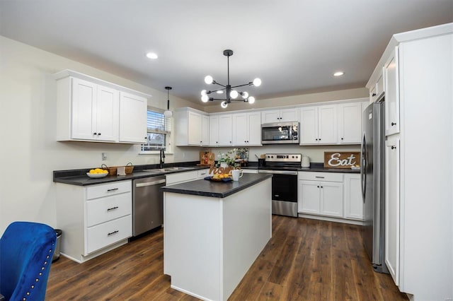 kitchen with decorative light fixtures, stainless steel appliances, a center island, and white cabinets