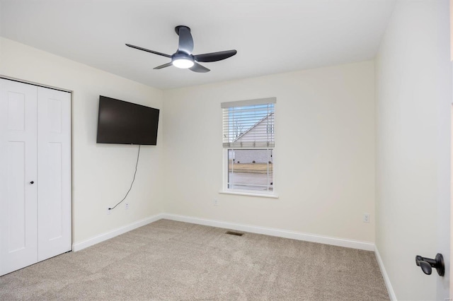 unfurnished bedroom with light colored carpet, ceiling fan, and a closet