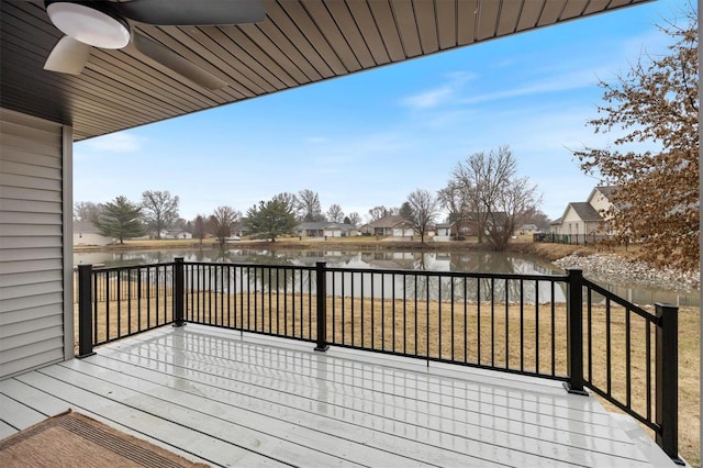 wooden deck with a water view, ceiling fan, and a lawn