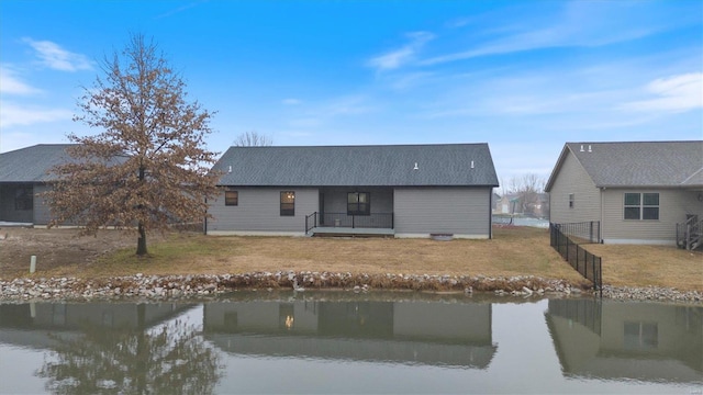 rear view of house featuring a lawn and a water view