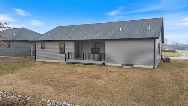 rear view of property featuring a lawn and central air condition unit