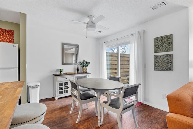 dining area featuring dark wood-type flooring, ceiling fan, and a textured ceiling