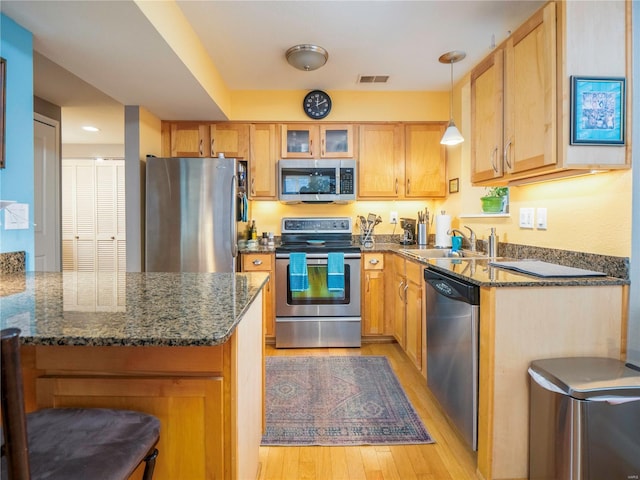 kitchen with dark stone countertops, sink, pendant lighting, and stainless steel appliances