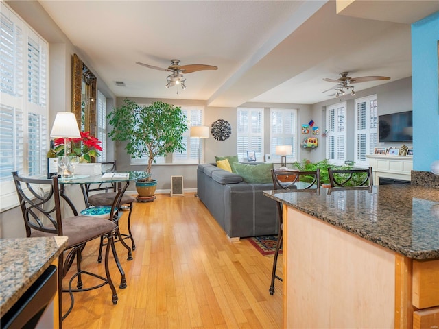 kitchen with a kitchen breakfast bar, ceiling fan, and light hardwood / wood-style floors