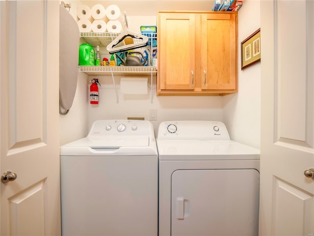 clothes washing area with separate washer and dryer and cabinets