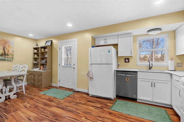 kitchen with sink, white cabinetry, wood-type flooring, dishwasher, and white fridge