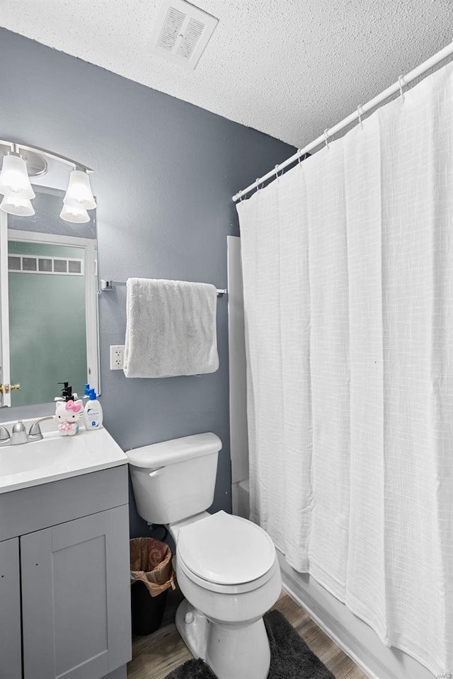 full bathroom with toilet, a textured ceiling, vanity, shower / bath combo with shower curtain, and hardwood / wood-style flooring