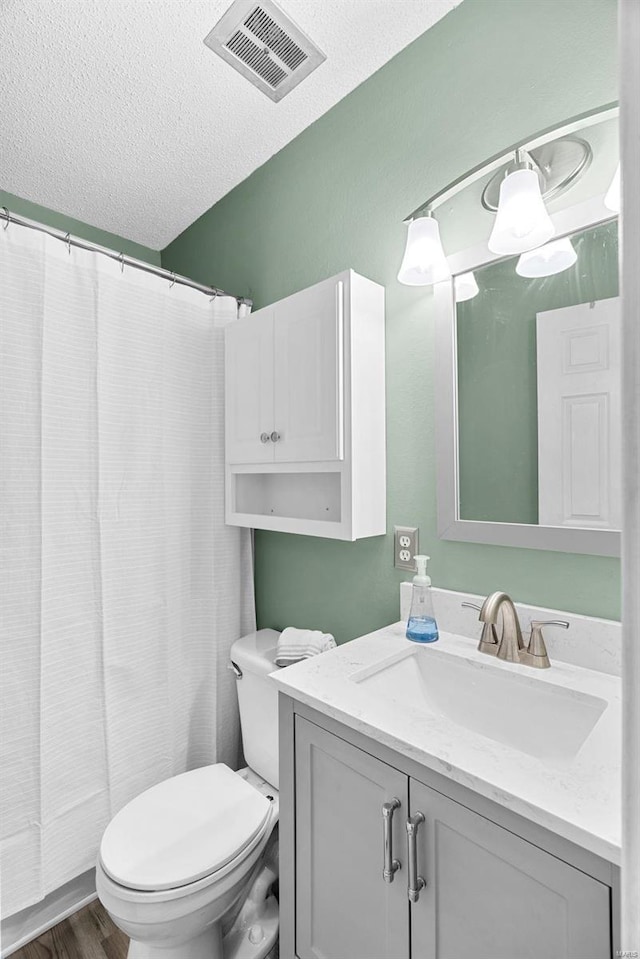 bathroom featuring hardwood / wood-style flooring, vanity, toilet, and a textured ceiling