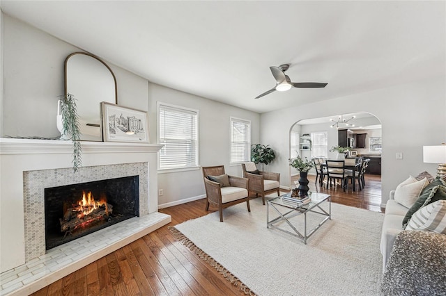 living room with hardwood / wood-style flooring, a tile fireplace, and ceiling fan