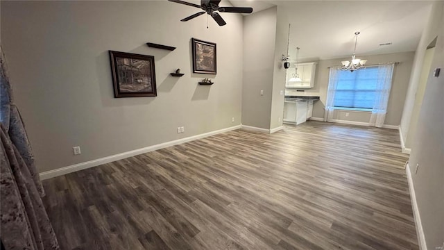 unfurnished living room with dark hardwood / wood-style floors and ceiling fan with notable chandelier