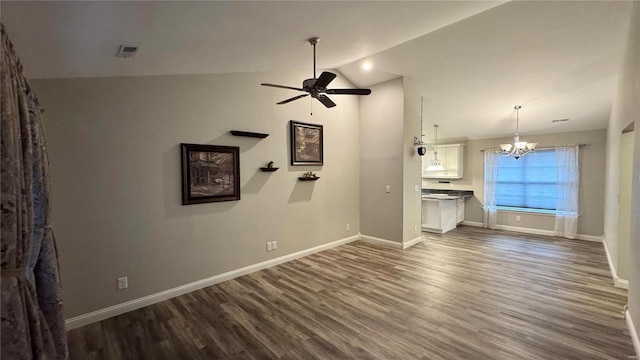 unfurnished living room with dark wood-type flooring, vaulted ceiling, and ceiling fan with notable chandelier