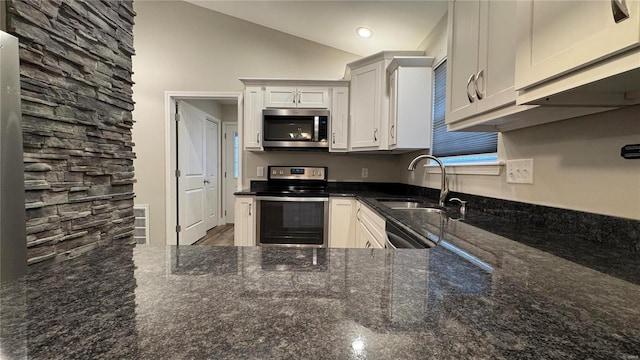 kitchen featuring sink, stainless steel appliances, dark stone counters, and white cabinets