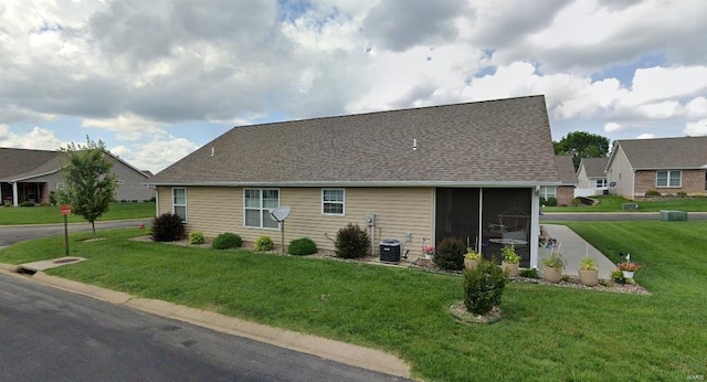 rear view of house with a yard, central AC, and a sunroom