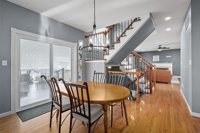 dining space featuring ceiling fan with notable chandelier and light hardwood / wood-style flooring