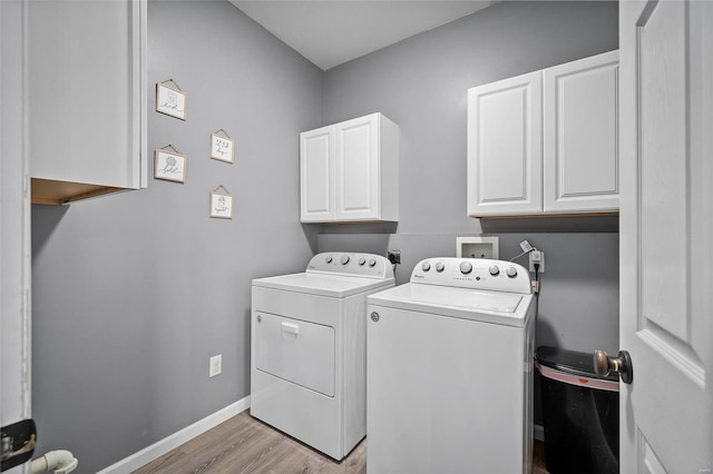 clothes washing area with cabinets, light hardwood / wood-style floors, and washing machine and dryer