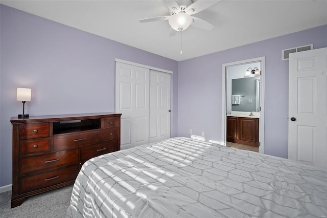 carpeted bedroom featuring ceiling fan, ensuite bath, and a closet