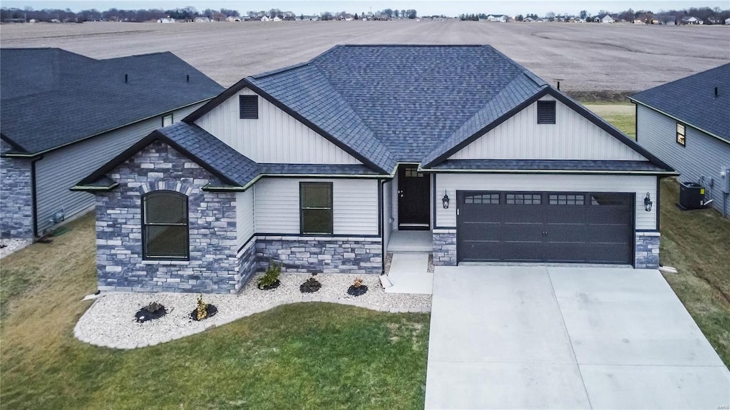 view of front of house featuring a rural view, a garage, a front yard, and central air condition unit