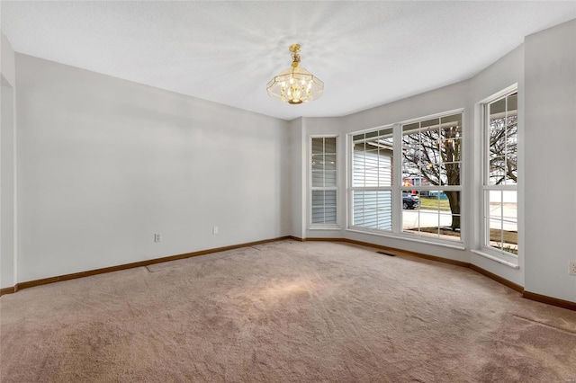 spare room featuring carpet floors and a notable chandelier