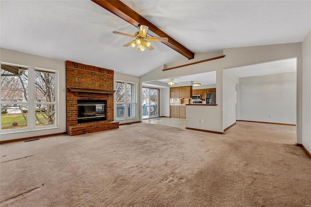 unfurnished living room with a wealth of natural light, a brick fireplace, vaulted ceiling with beams, and light colored carpet