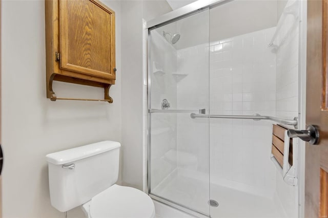 bathroom with a shower with door and toilet