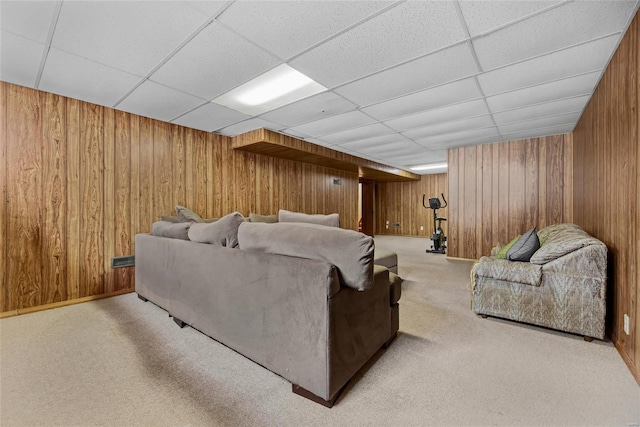 carpeted living room featuring a paneled ceiling and wood walls