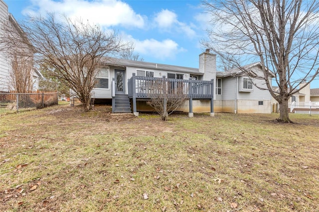 rear view of house featuring a wooden deck and a lawn