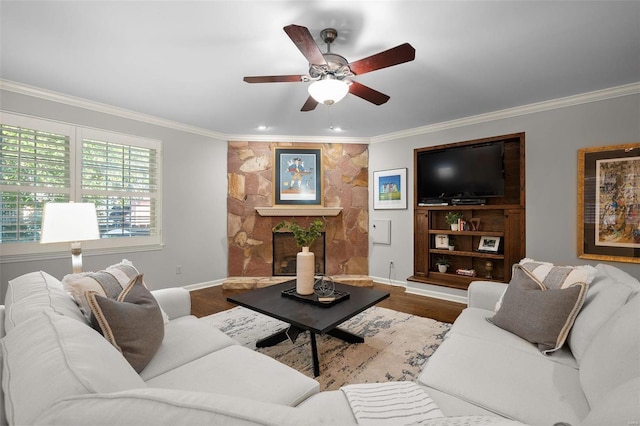 living room featuring crown molding, ceiling fan, wood-type flooring, and a fireplace