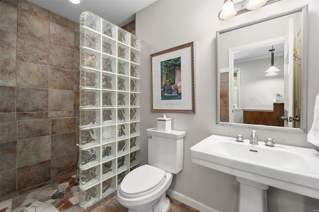 bathroom with ornamental molding, toilet, and tiled shower