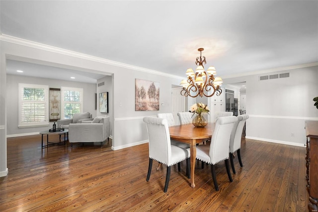 dining area with crown molding, dark wood-type flooring, and a chandelier