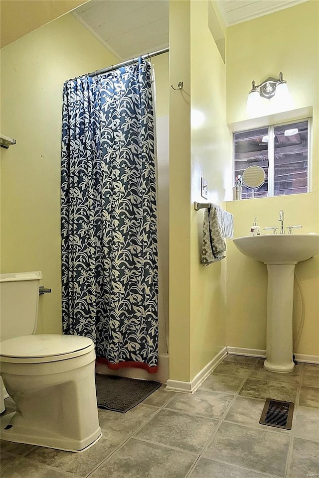 bathroom with shower / bathtub combination with curtain, crown molding, and toilet