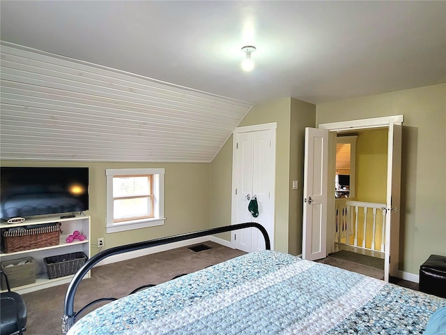 bedroom with lofted ceiling, dark carpet, and a closet