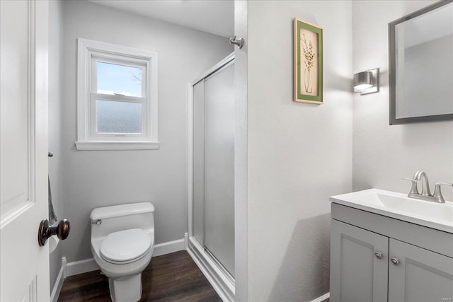 bathroom featuring hardwood / wood-style floors, toilet, a shower with shower door, and vanity