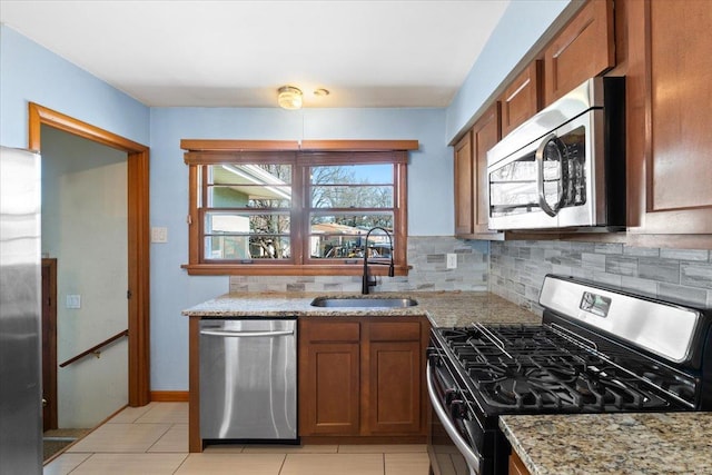 kitchen featuring light stone counters, appliances with stainless steel finishes, sink, and backsplash