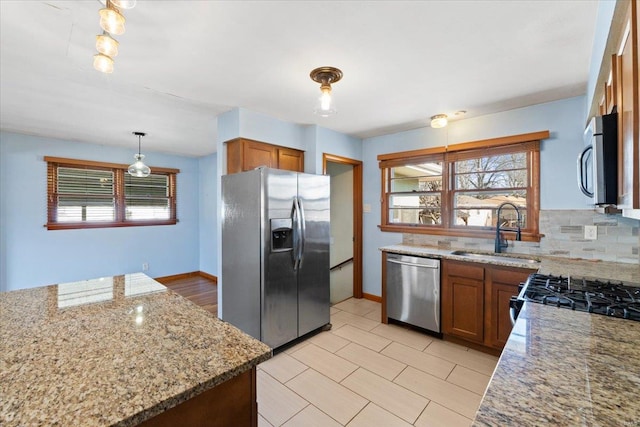 kitchen featuring pendant lighting, sink, light stone counters, and stainless steel appliances